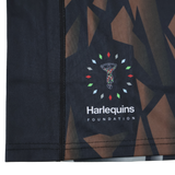 Close-up of the moisture-wicking fabric on the Castore Harlequins 23/24 Replica Third Jersey, showing its abstract geometric pattern and Harlequins Foundation logo with stylized figure amid colored shapes.