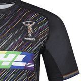 The Harlequins Replica Pride Jersey 23/24 by Castore is a black jersey with colorful diagonal stripes and the club’s iconic chest logo.