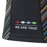 Close-up of the Harlequins Replica Pride Jersey 23/24 by Castore, featuring black fabric with multicolored diagonal stripes and "WE ARE TRUE" beneath a row of colored diamond shapes.