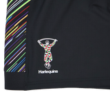 Close-up of black fabric on the Harlequins 23/24 Pro Pride Short by Castore, with multicolored diagonal stripes and the Harlequins logo—showcasing premium detail for athletic fit rugby shorts from Castore.