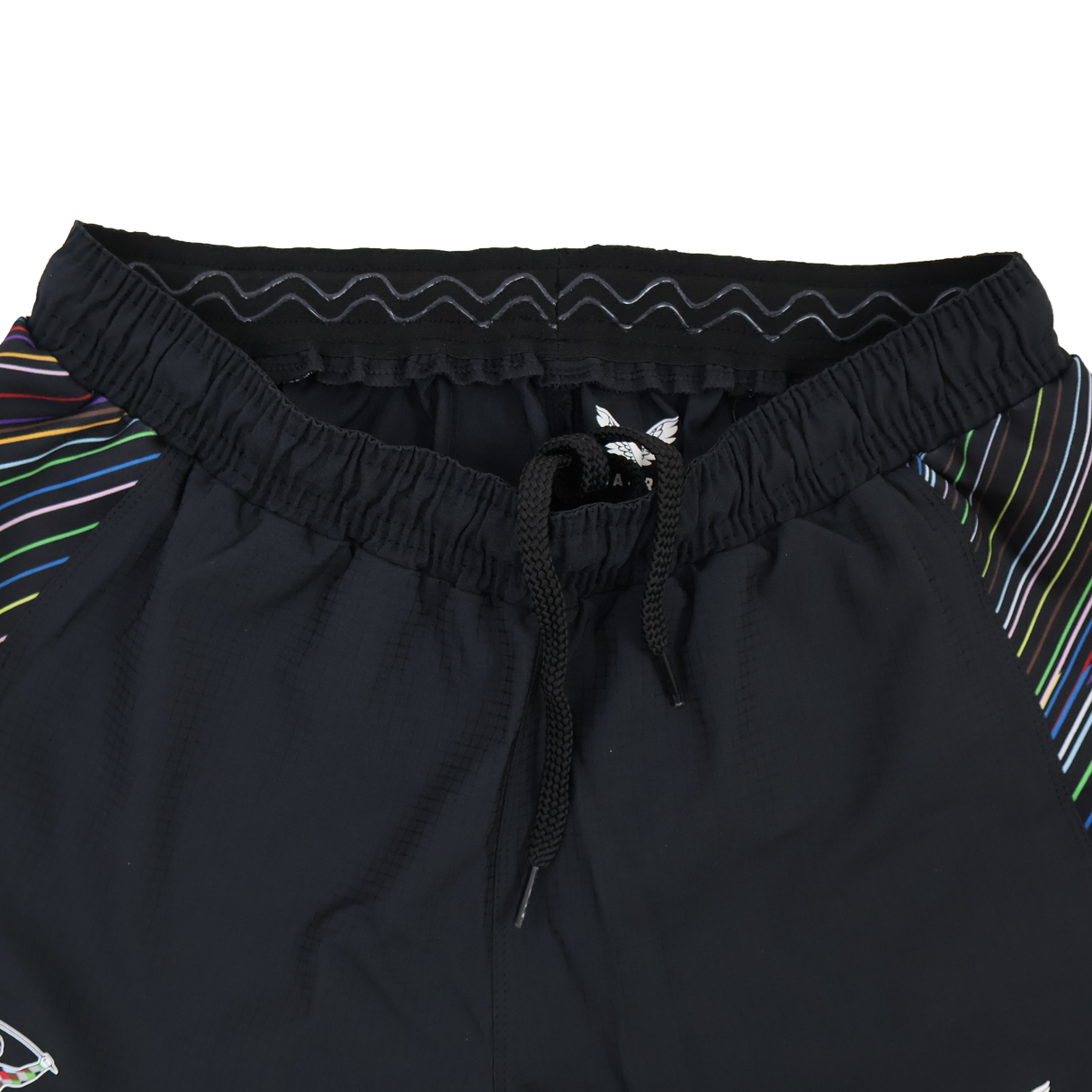 Close-up of the Harlequins 23/24 Pro Pride Short by Castore—black athletic fit rugby shorts featuring an elastic waistband, black drawstring, and colorful striped side accents.