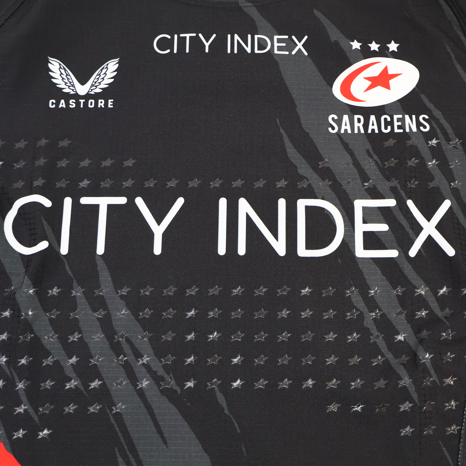 A close-up of the Saracens Pro Home Jersey 23/24 by Castore, a black rugby jersey showcasing Castore, City Index, and Saracens logos with a bold star pattern.