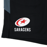Close-up of the Saracens logo on the black Saracens Pro Home Shorts 23/24 by Castore, featuring a red star and crescent in a white oval above "SARACENS" text.