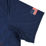 The USA Rugby 24/25 Pro Home Jersey by Castore is a navy blue short sleeve shirt inspired by the USA Rugby jersey, featuring a small American flag patch on the upper sleeve.
