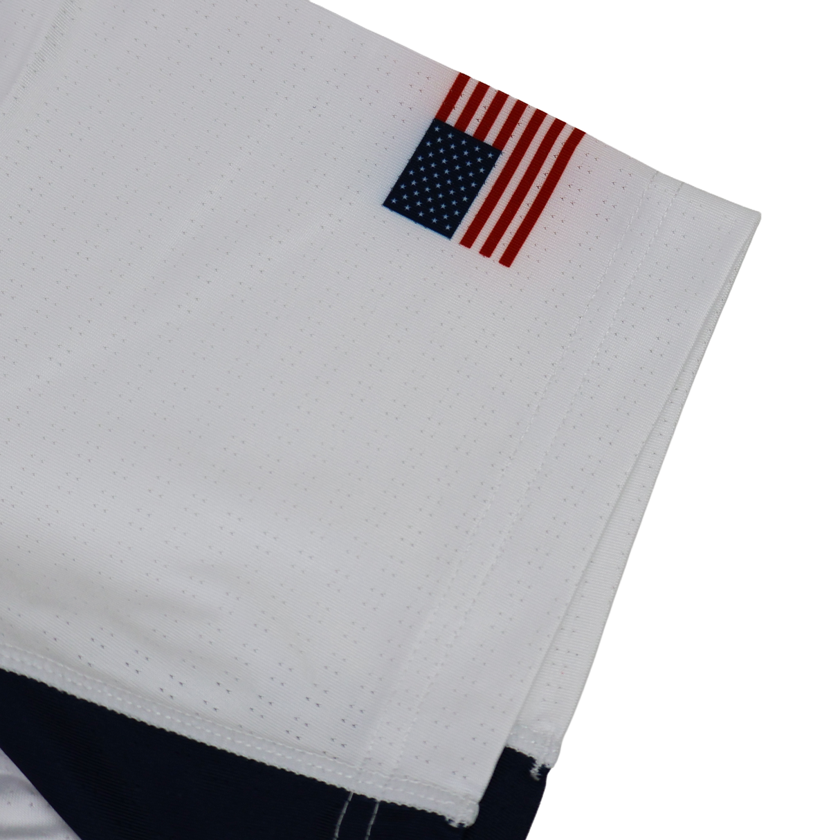 A small American flag patch is sewn onto the hem of the USA Rugby 24/25 Pro Away Jersey by Castore, featuring navy detailing and showcasing USA Rugby pride.