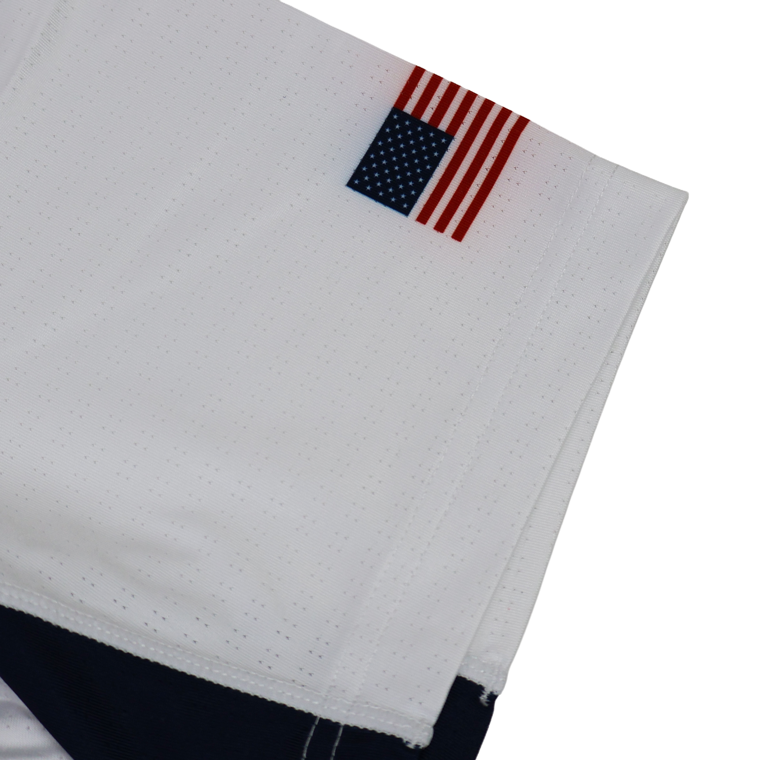 A small American flag patch is sewn onto the hem of the USA Rugby 24/25 Pro Away Jersey by Castore, featuring navy detailing and showcasing USA Rugby pride.