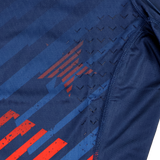 Close-up of the Castore USA Rugby 24/25 7s Olympic Pro Home Jersey’s navy athletic fabric, featuring red stripes, a subtle star pattern, and black chevron-textured grips near the seam.