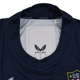 Close-up of the USA Rugby 24/25 7s Olympic Pro Home Jersey collar by Castore, showing the brand label, size tags, and "Made in China" text. A portion of the USA Rugby badge is visible on the right.