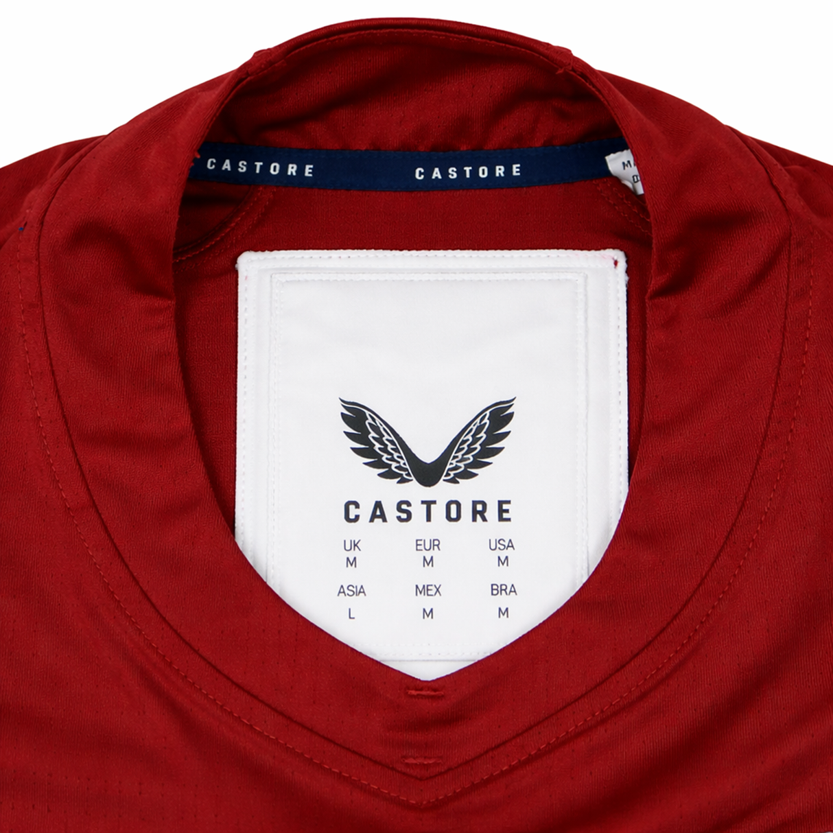 Close-up of the inside collar on the USA Rugby 24/25 Pro Training Jersey by Castore, showcasing the brand label, size chart, and signature winged logo—an official Castore USA Rugby design.
