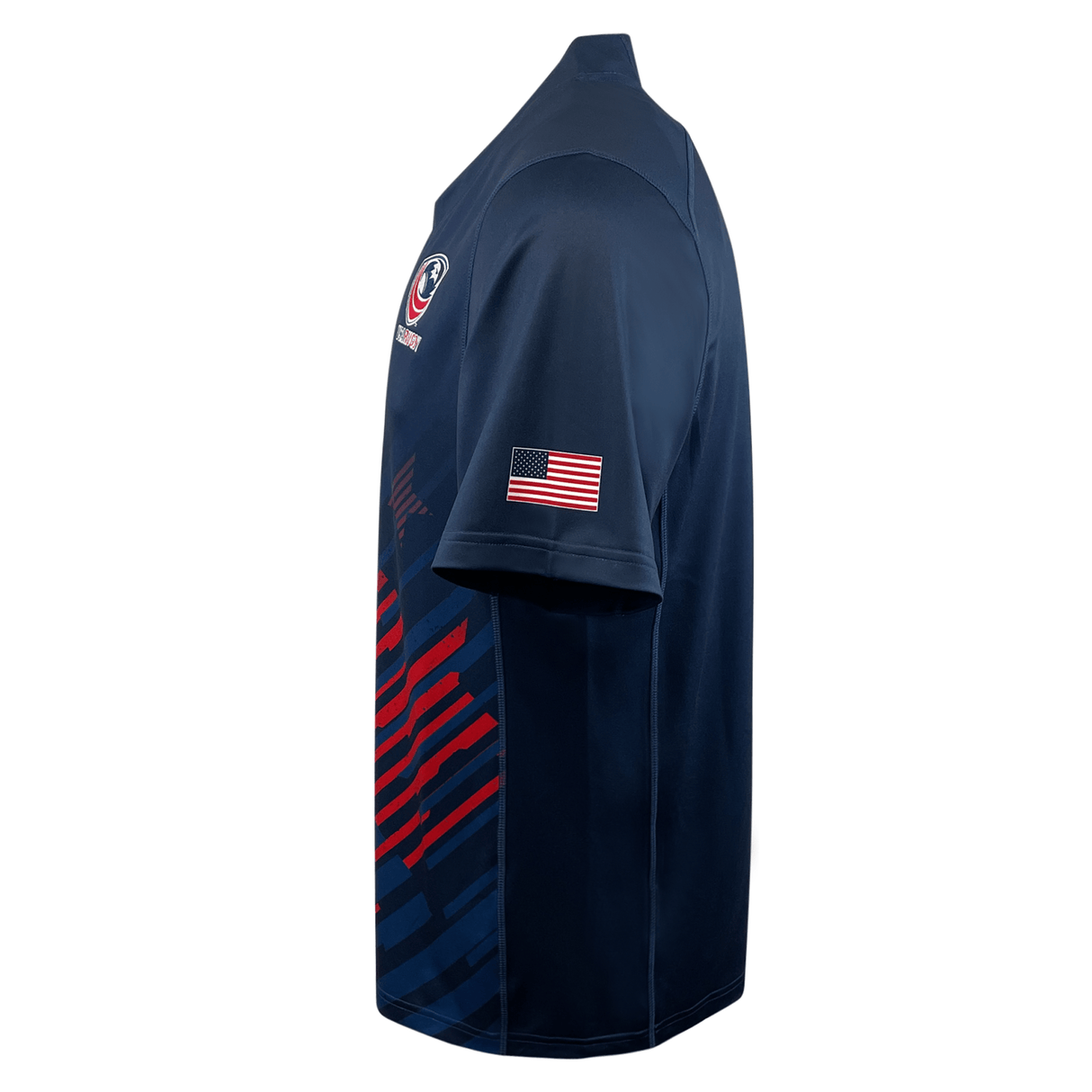 The Castore USA Rugby 23/24 Replica Home Jersey features navy blue, short sleeves, moisture-wicking fabric, a US flag patch on the right sleeve, and abstract red and blue graphics on the lower side.