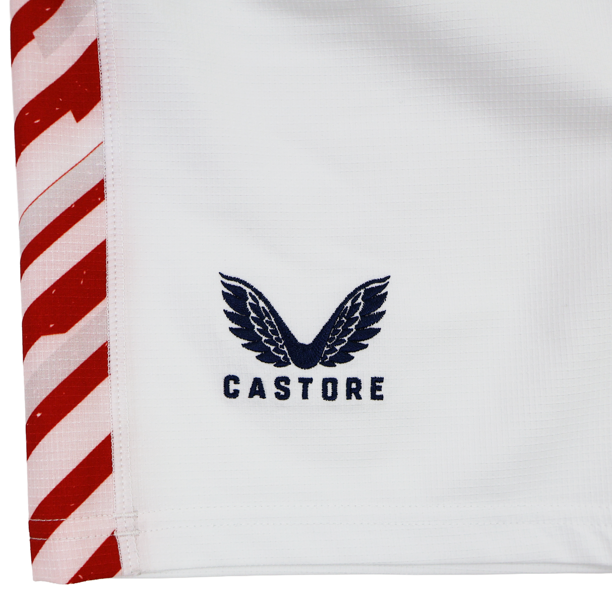 Close-up of the USA Rugby 24/25 7s Olympic Pro Away Short by Castore, showing white fabric with bold red and white diagonal edge stripes, the USA Rugby logo, and Castore’s signature black wing design.