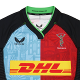 The Harlequins 24/25 Pro Home Jersey by Castore features light blue and red halves, black sleeves, Castore branding, and a bold yellow DHL sponsor logo across the chest.