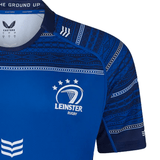 A close-up of the Leinster 24/25 Home Replica Jersey by Castore, showcasing blue fabric with white patterns, the Leinster Rugby logo, and sponsor branding on the chest and right sleeve.