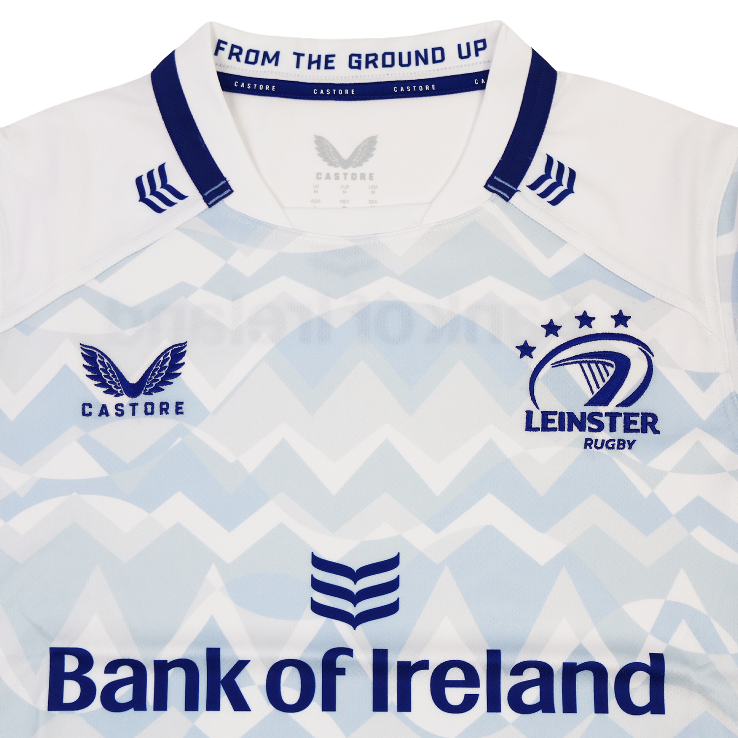 A close-up of the Leinster 24/25 Replica Away Jersey by Castore highlights the Leinster Rugby crest and Bank of Ireland sponsor on a light blue and white zigzag design.