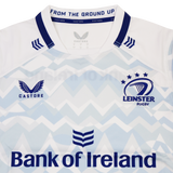 A close-up of the Leinster 24/25 Replica Away Jersey by Castore highlights the Leinster Rugby crest and Bank of Ireland sponsor on a light blue and white zigzag design.