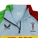 Close-up of the Harlequins 24/25 Matchday 1/4 Zip Midlayer by Castore in light blue, showcasing a partial zip, Castore and DHL logos, and the iconic Harlequins team crest.