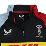 Close-up of the Harlequins 24/25 Matchday 1/4 Zip Midlayer by Castore, showcasing sponsor logos, a quarter-zip collar, and a bold multicolored panel design.