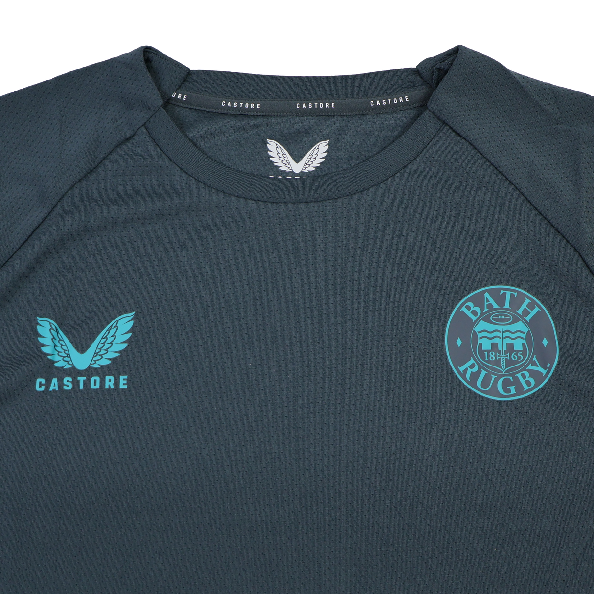The Bath 24/25 Pro Players Long Sleeve Tee by Castore is a dark gray top featuring the Castore logo on the left chest and Bath Rugby club crest on the right—ideal as a training or casual shirt.