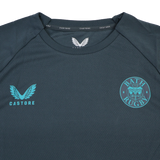 The Bath 24/25 Pro Players Long Sleeve Tee by Castore is a dark gray top featuring the Castore logo on the left chest and Bath Rugby club crest on the right—ideal as a training or casual shirt.