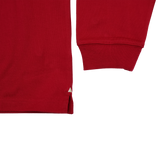 Close-up of the Scarlets 24/25 Retro Rugby Jersey by Castore, a red long-sleeve shirt inspired by classic rugby style, highlighting the cuff, lower hem with side slit, and set against a plain white background.