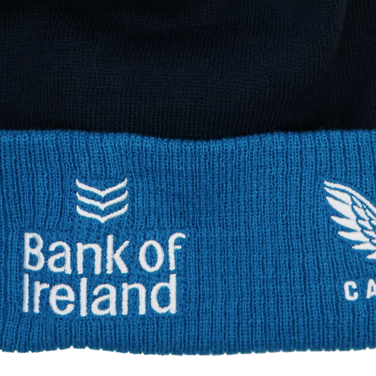 Close-up of the Leinster Bobble Beanie 24/25 by Castore, showing blue and black knit fabric with "Bank of Ireland" and logo embroidered in white—ideal detail for this official Castore beanie.