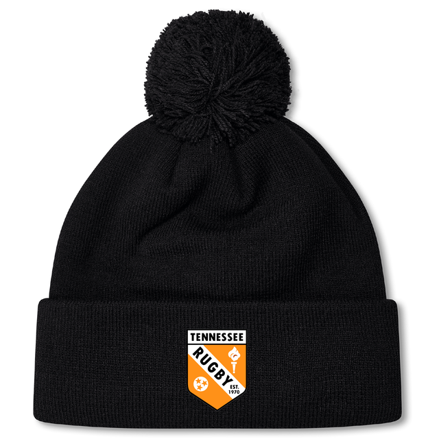The University of Tennessee Pom Pom Beanie by EMB Canterbury features a black knit design, fleece lining for warmth, a pom-pom top, and a "Tennessee Rugby" crest logo on the front cuff.