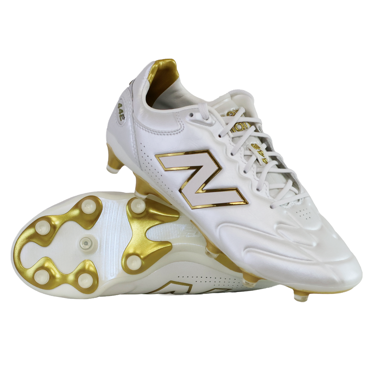 A pair of New Balance 442 Elite FG v3 soccer cleats in Sea Salt/Gold Metallic, one upright and one on its side, showcase DynamicTouch Tech for superior control and gold-accented firm ground studs.