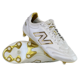 A pair of New Balance 442 Elite FG v3 soccer cleats in Sea Salt/Gold Metallic, one upright and one on its side, showcase DynamicTouch Tech for superior control and gold-accented firm ground studs.
