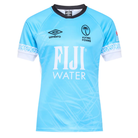 The Fiji 25/26 Replica Away Jersey by Umbro is a light blue rugby jersey with white accents, subtle Fijian masi art, "FIJI WATER" sponsor logo, Umbro branding, and the Flying Fijians emblem on the chest.