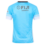 The Umbro Fiji 25/26 Replica Away Jersey is light blue with white and black trim, features “FIJI AIRWAYS,” a circular logo, Fijian masi art on the back, has an athletic polyester fit, and is displayed against a plain background.