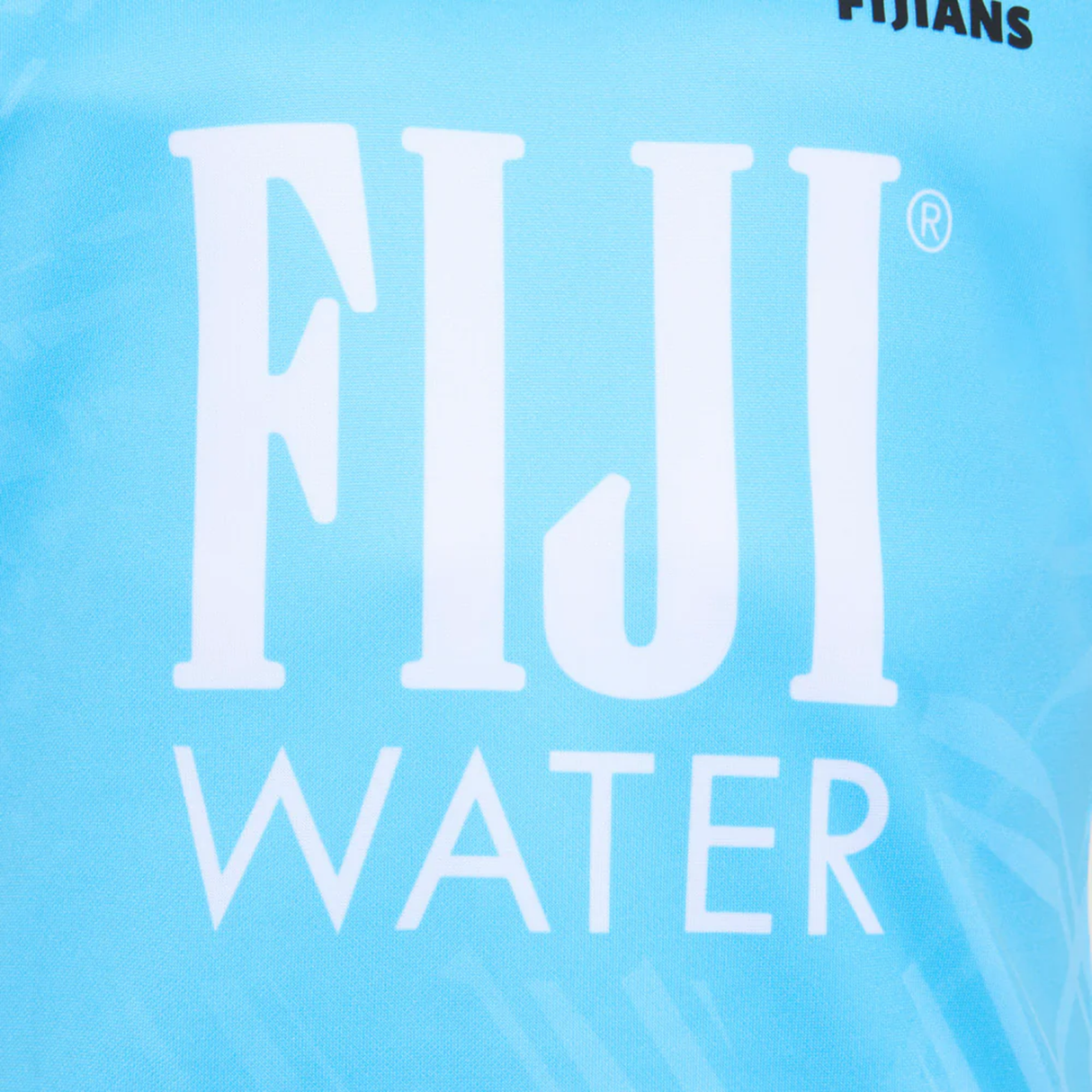 Close-up of the light blue Fiji 25/26 Replica Away Jersey by Umbro, featuring large white "FIJI WATER" text and a design inspired by traditional Fijian masi art.