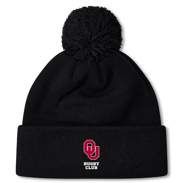 The University of Oklahoma Women Pom Pom Beanie by EMB Canterbury is a black beanie featuring a large pom-pom and a front logo with a red "O," "U," and "Rugby Club" in white. Fleece-lined for warmth, it's ideal for chilly days to display your Canterbury Rugby pride.
