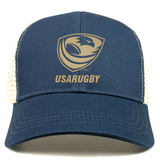 The EMB S&S Activewear USA Rugby Bronze Eco Trucker Hat features a gold logo and text on navy blue organic cotton, plus a breathable mesh back for eco-friendly comfort.