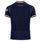 Back of the USA Rugby 24/25 Authentic Matchday Home Jersey by Macron in navy, with red, white, and blue trim and a small American flag patch on the right sleeve—official gear from Macron.