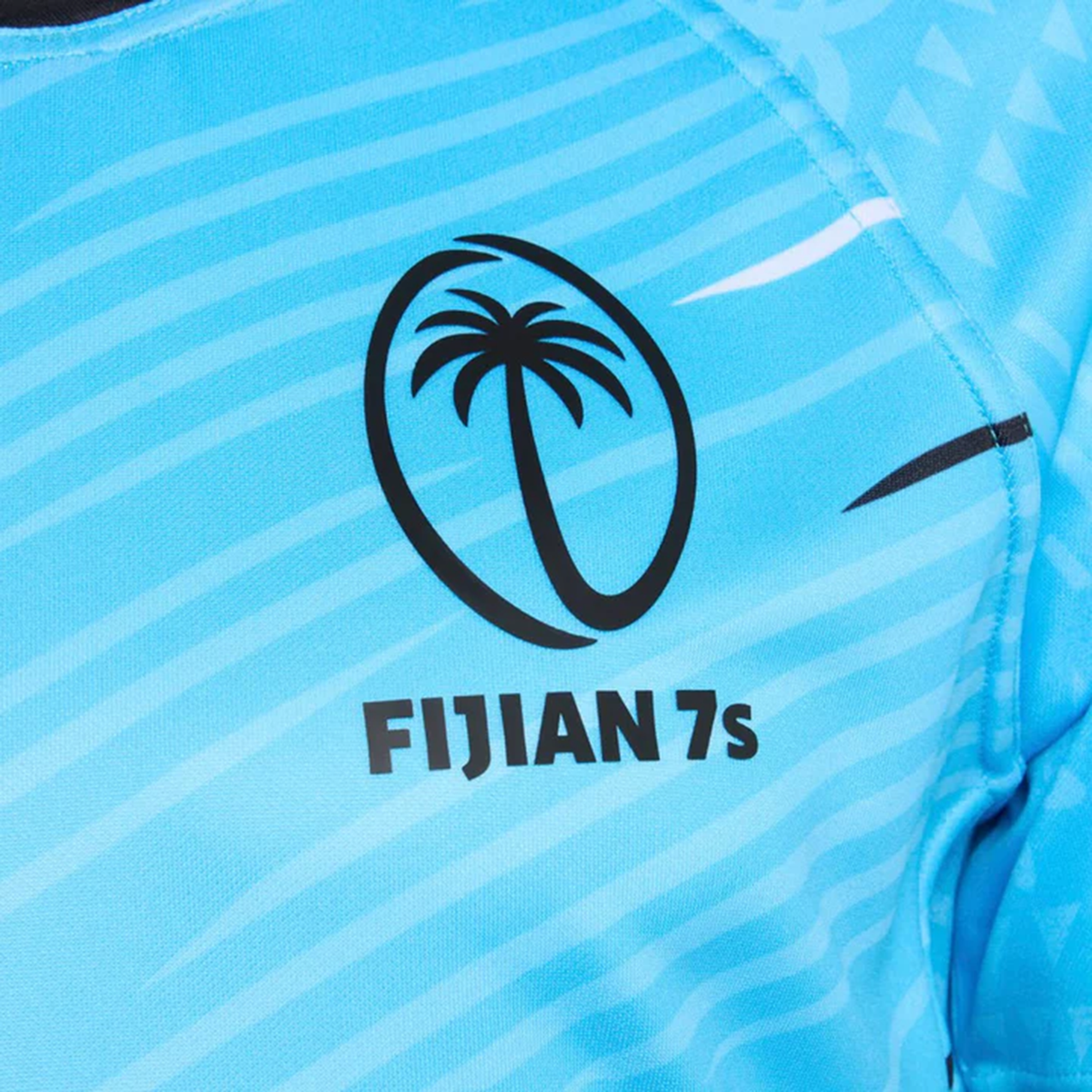 A close-up of the Fiji 7's 25/26 Replica Away Jersey by Umbro, featuring a blue design with a palm tree logo and bold "FIJIAN 7s" text, created as the official away jersey for the Fiji 7's team.