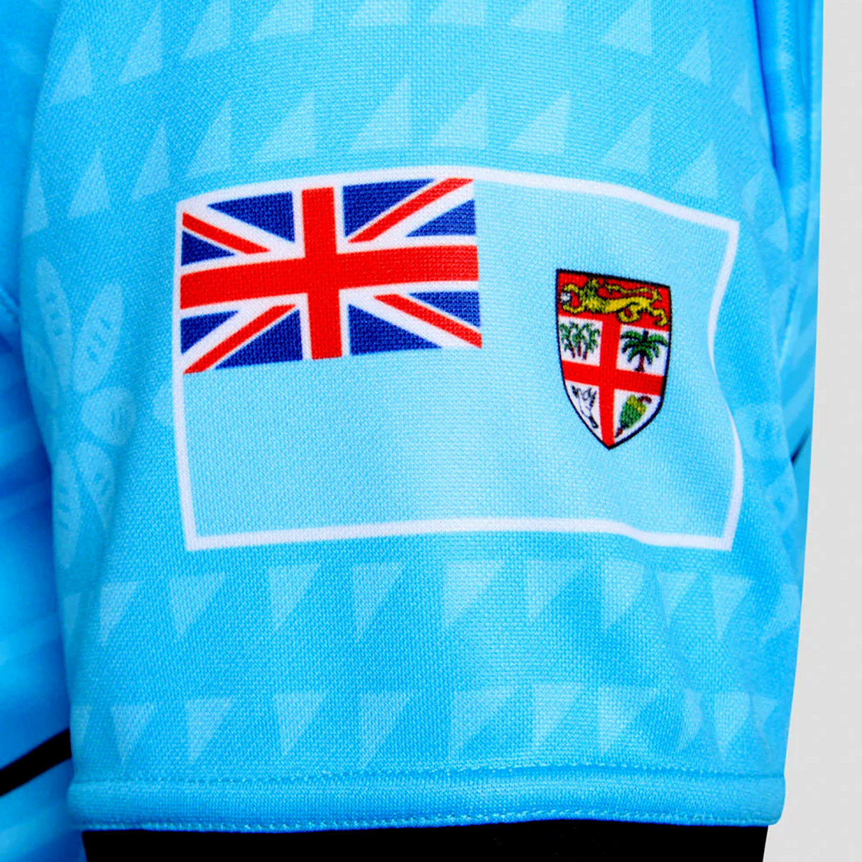 Close-up of the Fiji 7's 25/26 Replica Away Jersey by Umbro, displaying Fijian masi art details and the Fiji national flag on the sleeve.