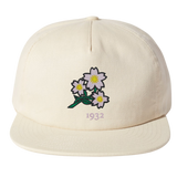The Nations of Rugby Japan Vintage Brushed Cotton Cap by EMB Weld features embroidered white flowers with yellow centers and green stems above the number "1932.