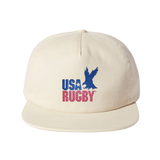 The USA Rugby Throwback Brushed Cotton Cap by EMB Weld is a beige cap made from brushed cotton twill, showcasing "USA RUGBY" and a blue eagle logo on the front, perfect for rugby enthusiasts.
