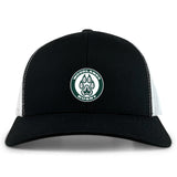 The Woodlands Youth Retro Trucker Cap by EMB S&S Activewear features a black and white design, a circular "Woodlands Rugby" paw print embroidery on the front, and an adjustable snapback closure.