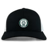 The Woodlands Youth Retro Trucker Cap by EMB S&S Activewear features a black and white design, a circular "Woodlands Rugby" paw print embroidery on the front, and an adjustable snapback closure.