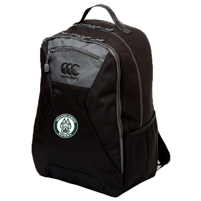 The Woodlands Youth Medium Backpack by Canterbury (EMB Canterbury) features black fabric with grey accents, a front zipper pocket, side mesh pocket, padded laptop pocket, and a Woodlands Rugby logo patch on the front.