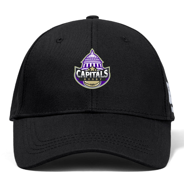 The Capitals Rugby NC Flexfit Drill Cap by EMB Canterbury is a black cap with a purple and white embroidered Capitals Rugby logo, featuring a capitol dome and rugby ball on the front.