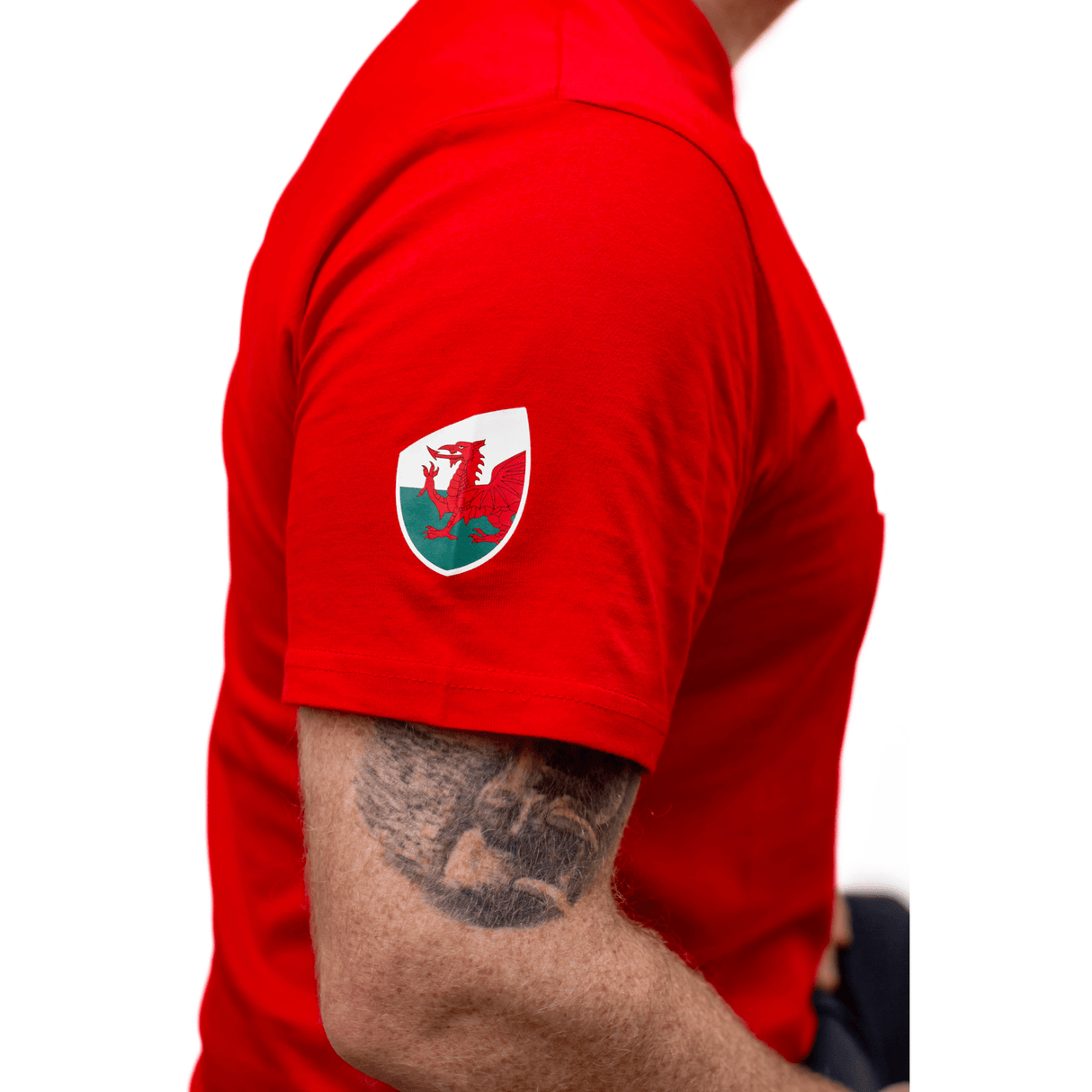 A man wearing a red Sportfolio Rugby World Cup 23 Wales Supporters T-Shirt with a tattoo on his arm supporting the WRU.