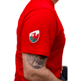 A man wearing a red Sportfolio Rugby World Cup 23 Wales Supporters T-Shirt with a tattoo on his arm supporting the WRU.