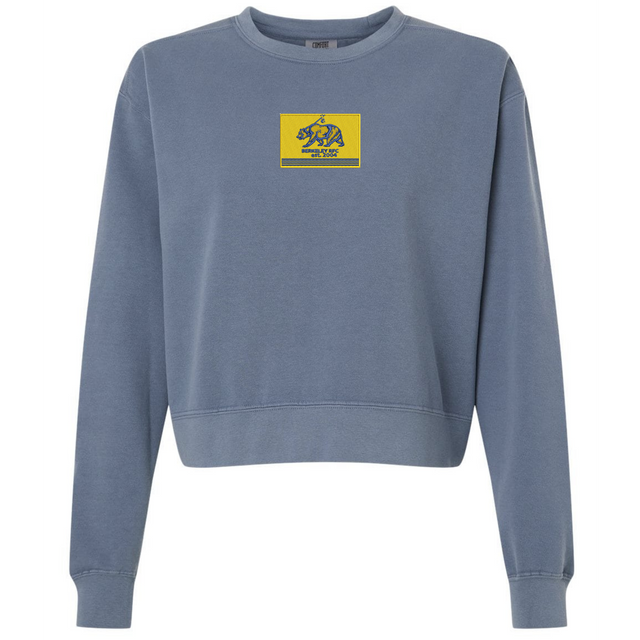 Berkeley RFC Women’s Garment-Dyed Mid-Length Crewneck Sweatshirt in blue, featuring a rectangular yellow chest patch with a blue bear icon and “Berkeley RFC Est. 2006” text.