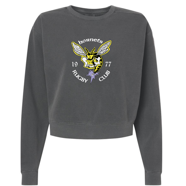 The EMB S&S Activewear Hornets Rugby Club 1977 Women's Garment-Dyed Mid-Length Crewneck Sweatshirt is a heavyweight fleece in charcoal gray, featuring a hornet graphic with "Hornets Rugby Club 1977" text and a purple flower below the hornet's head.