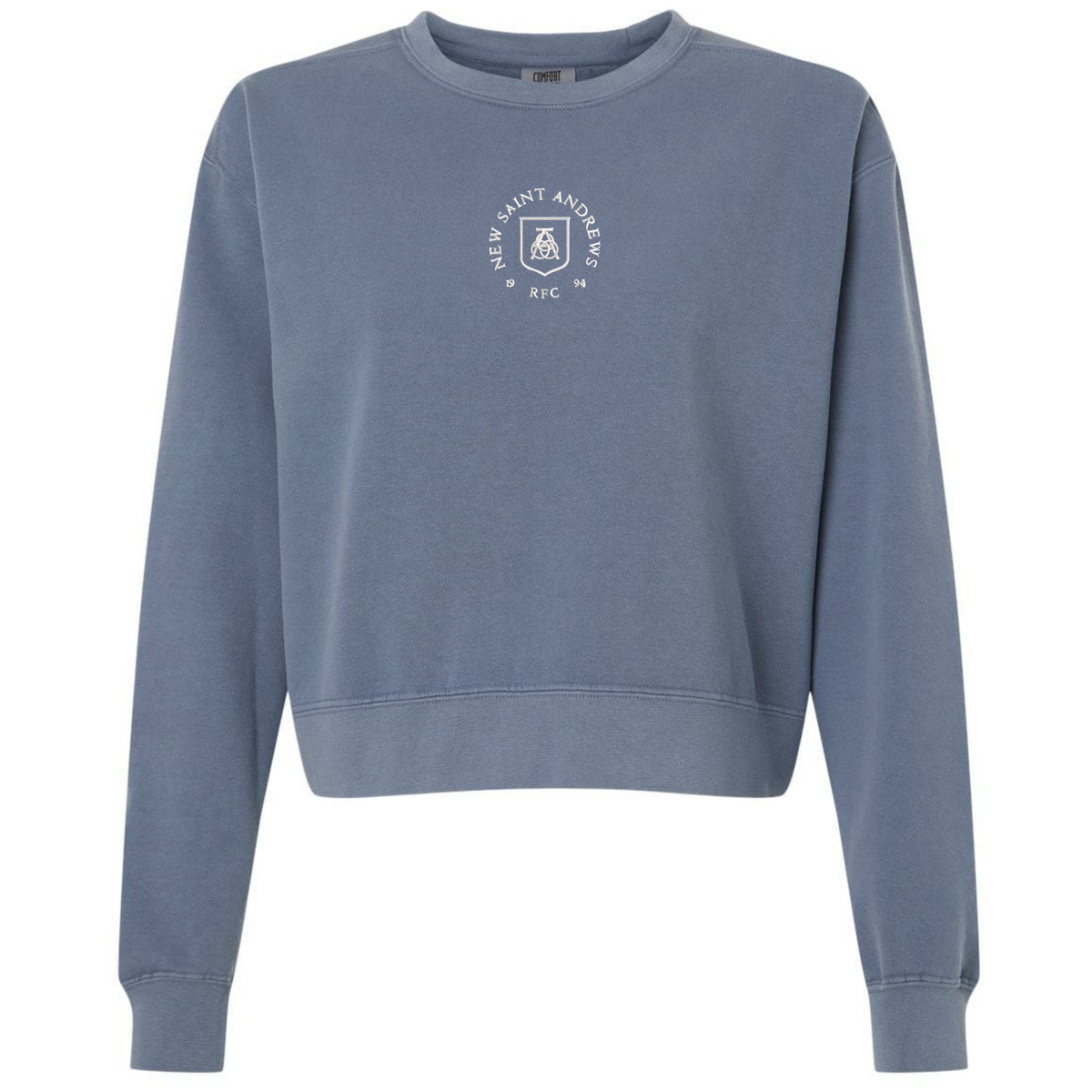 EMB S&S Activewear New Saint Andrews College women’s garment-dyed mid-length crewneck sweatshirt in blue heavyweight fleece, featuring long sleeves and a small white circular logo with “New Saint Andrews RFC ’94” printed on the chest.
