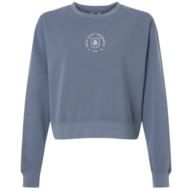 EMB S&S Activewear New Saint Andrews College women’s garment-dyed mid-length crewneck sweatshirt in blue heavyweight fleece, featuring long sleeves and a small white circular logo with “New Saint Andrews RFC ’94” printed on the chest.