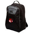 The Amoskeag Rugby Club Medium Backpack by EMB Canterbury is black, with a "Canterbury" logo and a stitched patch depicting a red and white shield with a black rugby goal post. It's made from durable 600D PVC and includes Vaposhield technology for weather protection.