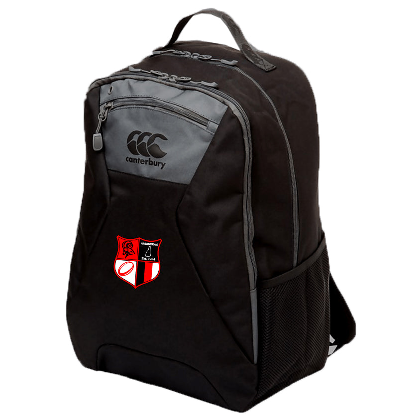 The Amoskeag Rugby Club Medium Backpack by EMB Canterbury is black, with a "Canterbury" logo and a stitched patch depicting a red and white shield with a black rugby goal post. It's made from durable 600D PVC and includes Vaposhield technology for weather protection.